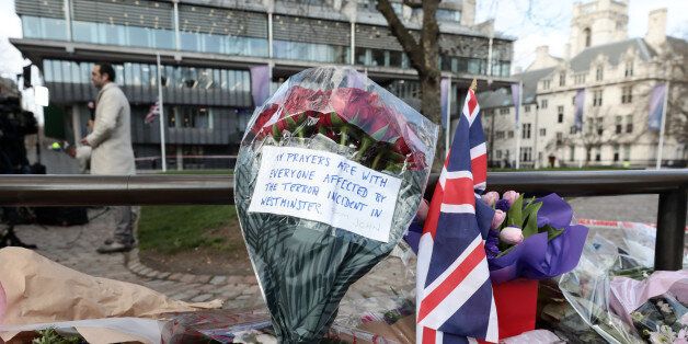 Flowers left in tribute to the victims of the terror attack stand next to a Union flag, also known as Union Jack, in central London, U.K., on Thursday, March 23, 2017. Parliament will return to work on Thursday after London's worst terror attack in more than a decade left five people dead, including the assailant and the police officer he stabbed. Photographer: Simon Dawson/Bloomberg via Getty Images