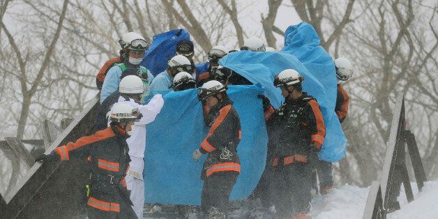Firefighters carry a survivor they rescued from the site of an avalanche in Nasu town, Tochigi prefecture on March 27, 2017.Eight high school students were feared dead on March 27 after being engulfed by an avalanche while on a mountain-climbing outing with dozens of others, officials said. / AFP PHOTO / JIJI PRESS / JIJI PRESS / Japan OUT (Photo credit should read JIJI PRESS/AFP/Getty Images)