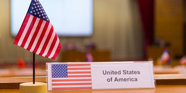 United States of America's small flag on meeting table, with blurred meeting room background