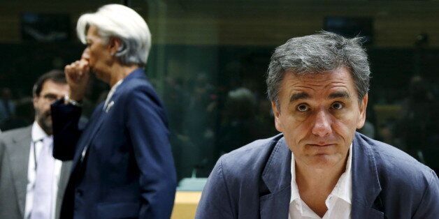 Greek Finance Minister Euclid Tsakalotos and International Monetary Fund (IMF) Managing Director Christine Lagarde (back L) attend a euro zone finance ministers meeting in Brussels, Belgium, July 12, 2015. Euro zone leaders will fight to the finish to keep near-bankrupt Greece in the euro zone on Sunday after the European Union's chairman cancelled a planned summit of all 28 EU leaders that would have been needed in case of a