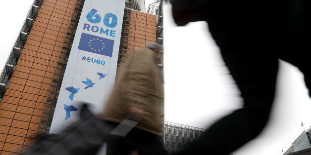 People walk past the European Commission headquarters in Brussels on which is displayed a banner celebrating the 60 years after the signing of the Treaty of Rome, in Brussels, Belgium March 20, 2017. REUTERS/Yves Herman