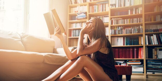 Woman dressed in a sexy lingerie reading a book and drinking her morning coffee.
