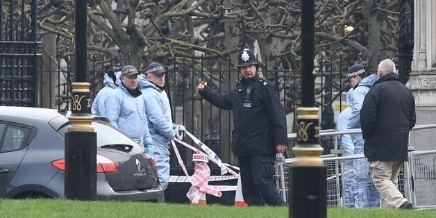 Police officers in forensics suits work at the scene on March 23, 2017 where the car collided with the gates of the Houses of Parliament during the March 22 terror attack in Westminster in central London. Britain's parliament reopened on Thursday with a minute's silence in a gesture of defiance a day after an attacker sowed terror in the heart of Westminster, killing three people before being shot dead. Sombre-looking lawmakers in a packed House of Commons chamber bowed their heads and police of