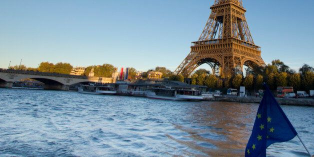 Eiffel Tower, Paris, at sunset as seen from Seine river with EU banner