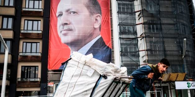 A man pulls a cart in front of a huge portrait of Turkish President Recep Tayyip Erdogan on Taksim Square in Istanbul on March 15, 2017. Turkey will hold its constitutional referendum on April 16, 2017. The controversial changes seek to replace the parliamentary system and move to a presidential system which would give President Recep Tayyip Erdogan executive authority. / AFP PHOTO / BULENT KILIC (Photo credit should read BULENT KILIC/AFP/Getty Images)