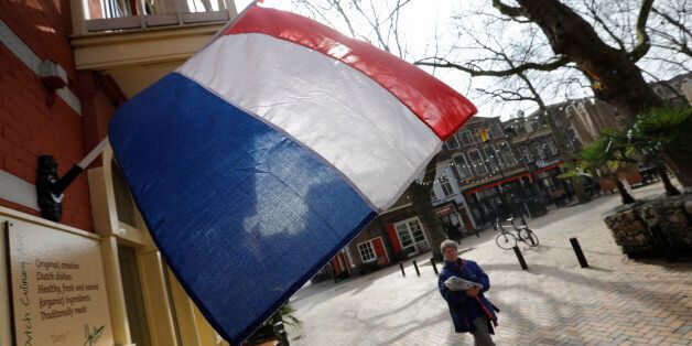 A woman walks past a national flag, the day before a general election, in Delft, Netherlands, March 14, 2017. REUTERS/Yves Herman
