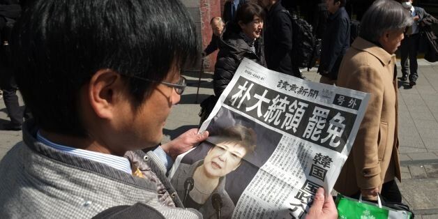 A man reads an extra edition of a Japanese major newspaper reporting on South Korean President Park Geun-hye's impeachment in Tokyo on March 10, 2017. South Korean President Park Geun-Hye was fired by the country's top court on March 10, as it upheld her impeachment by parliament over a wide-ranging corruption scandal. / AFP PHOTO / Kazuhiro NOGI (Photo credit should read KAZUHIRO NOGI/AFP/Getty Images)