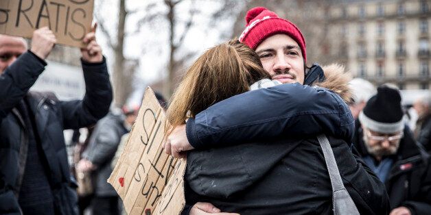 Paris, France - January 10, 2016: Young man hugging a lady during the ceremony Place de la Republique to commemorate victims of the bombing and shooting rampage, Charlie Hebdo terrorist attack and 'Marches Republicaines' demonstration