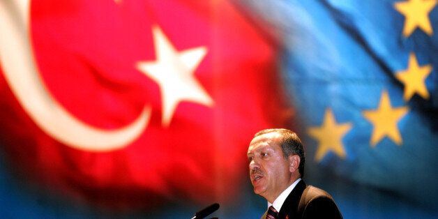 Turkey's Prime Minister Tayyip Erdogan makes a speech under Turkish and EU flags during a dinner