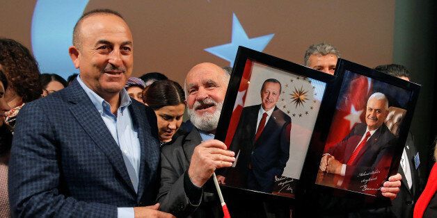Turkish Foreign Minister Mevlut Cavusoglu poses with a supporter holding portraits of Turkish President Recep Tayyip Erdogan and Prime Minister Binali Yildirim (R) at the end of a political rally on Turkey's upcoming referendum, in Metz, France, March 12, 2017. REUTERS/Vincent Kessler