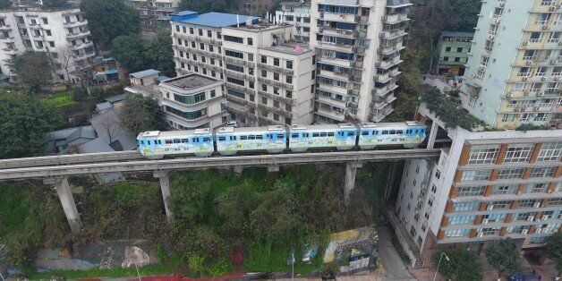 CHONGQING, CHINA - MARCH 18: A light railway train passes through a residential building on March 18, 2017 in Chongqing, China. Chongqing Rail Transit No.2 and a 19-storey residential building have been built across each other. The railway set its Liziba Station on the sixth to eighth floor in the building with noise reduction equipment. (Photo by VCG/VCG via Getty Images)