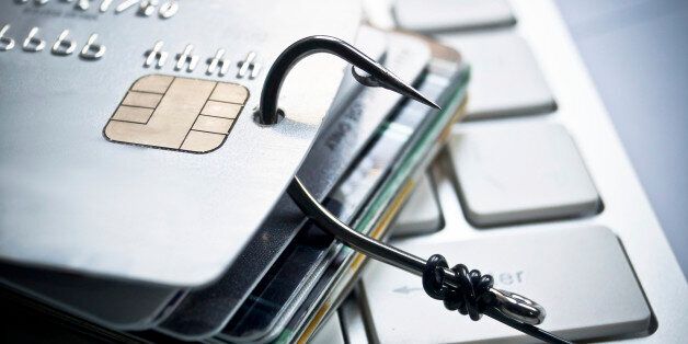 Phishing - a credit card with a fish hook trying to steal personal data on a computer keyboard / financial data theft