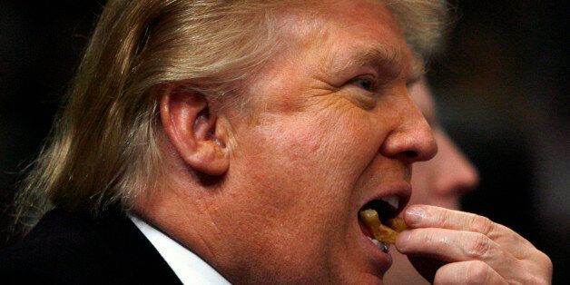 Donald Trump eats a french fry as the New York Knicks play Los Angeles Lakers in the first quarter of their NBA basketball game at Madison Square Garden in New York, January 30, 2007. REUTERS/Ray Stubblebine (UNITED STATES)
