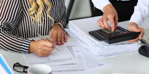 Two female accountants counting on calculator income for tax form completion hands closeup. Internal Revenue Service inspector checking financial document. Planning budget, audit concept