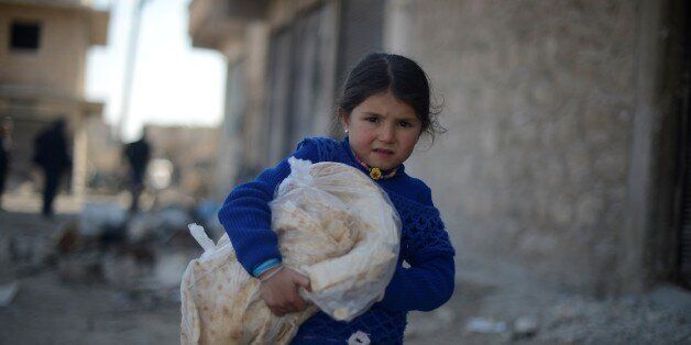ALEPPO, SYRIA - MARCH 07: A Syrian girl carries a pile of bread, provided by the Foundation for Human Rights and Freedoms and Humanitarian Relief (IHH), a Turkish NGO in Al-Bab town of Aleppo, Syria on March 07, 2017. Syrians who have returned to their home after the Al Bab town center has been entirely freed from Daesh terrorists as part of the 'Operation Euphrates Shield', prepare to start a new life in the area. The Turkish-led Operation Euphrates Shield began on August 24, 2016 to improve security, support coalition forces and eliminate the terror threat along the Turkish border using Free Syrian Army fighters backed by Turkish artillery and jets. (Photo by Huseyin Nasir/Anadolu Agency/Getty Images)
