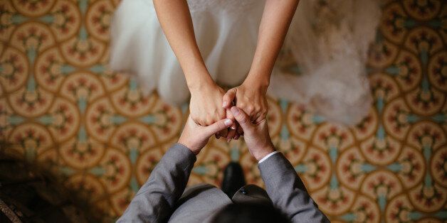 A close up shot of a bride and groom holding hands from a top view.