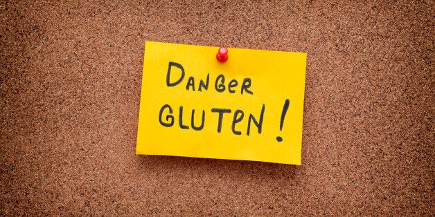 Paper note with the words Danger Gluten on cork board. Celiac Disease concept. Close up.