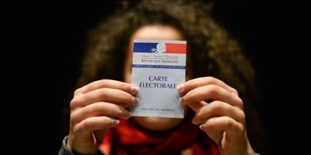 A woman holds her first electoral card, on March 19, 2017, in Besancon, eastern France. / AFP PHOTO / SÃ©bastien BOZON (Photo credit should read SEBASTIEN BOZON/AFP/Getty Images)