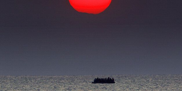 A red sun is seen over a dinghy overcrowded with Syrian refugees drifting in the Aegean sea between Turkey and Greece after its motor broke down off the Greek island of Kos, August 11, 2015. To match Special Report EUROPE-MIGRANTS/TURKEY-CHILDREN REUTERS/Yannis Behrakis/File Photo TPX IMAGES OF THE DAY