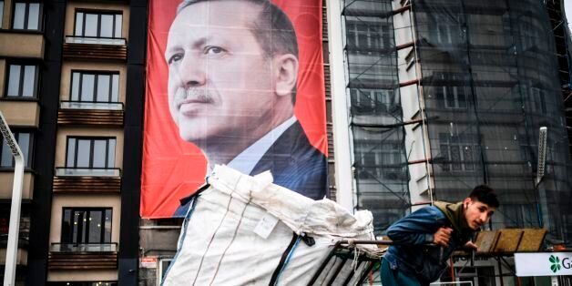 TOPSHOT - A man pulls a cart in front of a huge portrait of Turkish President Recep Tayyip Erdogan on Taksim Square in Istanbul on March 15, 2017. Turkey will hold its constitutional referendum on April 16, 2017. The controversial changes seek to replace the parliamentary system and move to a presidential system which would give President Recep Tayyip Erdogan executive authority. / AFP PHOTO / BULENT KILIC (Photo credit should read BULENT KILIC/AFP/Getty Images)