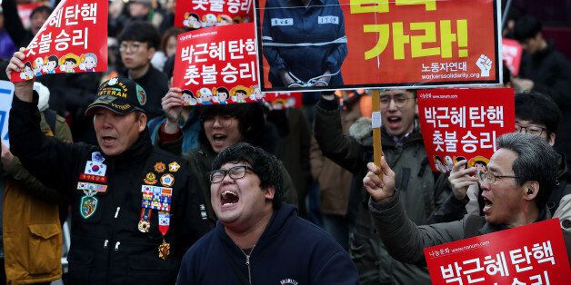 A demonstrator demanding South Korean President Park Geun-hye's impeachment holds a sign featuring a photograph of Park and shout slogans during a protest outside the Constitutional Court of Korea ahead of the court's ruling in Seoul, South Korea, on Friday, March 10, 2017. Any successor to Park will inherit a struggling economy that faces heightened risks from China and the U.S., its biggest trading partners, as well as record household debt. Photographer: SeongJoon Cho/Bloomberg via Getty Images