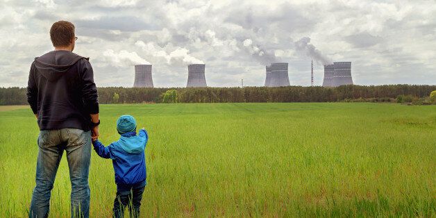 Pollution. Environmental problem. Father and his son looking on a emissions of plant. Factory chimneys (smoke stacks) polluting air on a green field. Nuclear power plant. Ecology concept. Copy space.