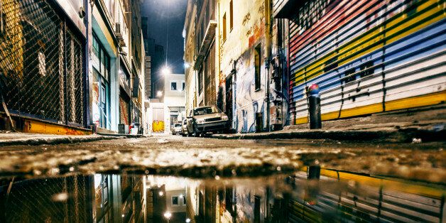 Graffiti covered ghetto streets reflected in puddle.