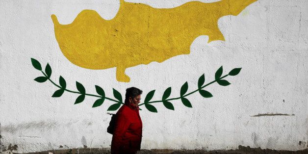 A woman walks in front of Cypriot flag painted on a wall in capital Nicosia, Cyprus February 22, 2017....