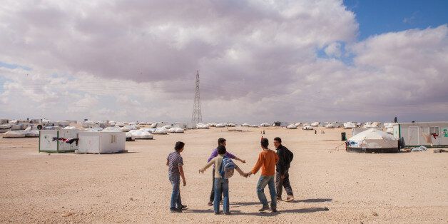 Young Syrian boys having fun at Zaatari Syrian refugee camp in northern Jordan, across the border from Syria, under a blue and cloudy winter sky.