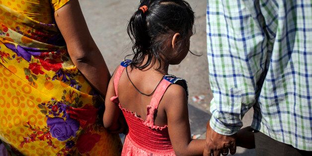 MAHARASHTRA, INDIA - NOVEMBER 12: 5 year old Nirmala (name changed), who was raped by her mother's boss, holds her parents hands as they walk down the street on November 12, 2015 in Maharashtra, India. One day Nirmala's mother gave her money to go to the corner store and buy food. While Nirmala was walking the man came up to her and offered to buy her candy. He took her to a wooded area behind an apartment building complex, raped her, and inserted a pen inside her. He left her naked and bleeding heavily. She required two surgeries and stayed in the hospital for three months. They caught the man two weeks later. Since he's been in jail, his family keeps coming to Nirmala's family offering them money to drop the court case. Nirmala's family has since moved to a different neighborhood because the neighbors were gossiping, saying things like 'The girl's life is spoiled, what will you do now?'. Nirmala's mother says they won't accept the money offered by the rapist's family, that they want justice instead. (Photo by Getty Images)