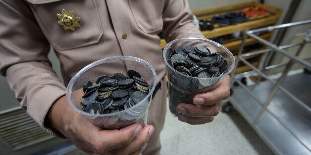 BANGKOK, THAILAND - MARCH 06: An officer shows the coins that the Sea Turtle ate over the years collected in two big glasses, in Bangkok, Thailand on March 06, 2017. The Sea turtle was suffering from various diseases due to the large quantity of coins that the animal ate over the year at the bottom of the pond. Veterinarian Nantarika Chansue wrote on her Facebook Page, to ask people not to throw coins at aquatic life. (Photo by Guillaume Payen/Anadolu Agency/Getty Images)