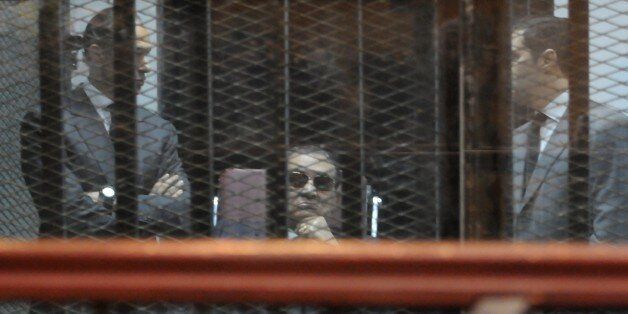 ADDING INFORMATION Ousted Egyptian president Hosni Mubarak, flanked by his two sons Gamal (L) and Alaa, sits in the defendants cage during his verdict hearing in a retrial for embezzlement on May 9, 2015 in the capital Cairo. The Egyptian court sentenced Mubarak and his two sons to three years in prison. AFP PHOTO / STR (Photo credit should read -/AFP/Getty Images)