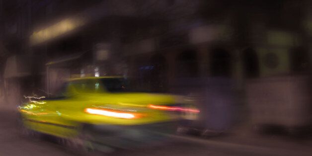 blurred image of a yellow taxi in night Athens