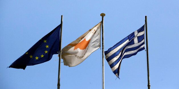The European Union (EU) flag, left, is seen flying alongside the Cypriot national flag, center, and the Greek national flag in Nicosia, Cyprus, on Sunday, April 22, 2012. Cyprus's budget deficit widened to 6.3 percent of gross domestic product last year from 5.3 percent of GDP in 2010, according to an e-mailed statement from the European Union's statistics agency. Photographer: Chris Ratcliffe/Bloomberg via Getty Images
