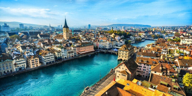 Aerial view of Zurich, Switzerland. Taken from a church tower overlooking the Limmat River. Beautiful blue sky with dramatic cloudscape over the city. Visible are many traditional Swiss houses, bridges and churches.