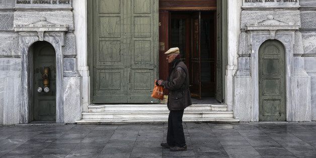 An elderly man walks past the entrance to the headquarters of the National Bank of Greece SA in Athens, Greece, on Tuesday, Feb. 28, 2017. Greeces auditors are pulling together a list of policies the country needs to implement to unlock additional bailout funds as talks with Athens resumed on Tuesday, two people familiar with the matter said. Photographer: Yorgos Karahalis/Bloomberg via Getty Images