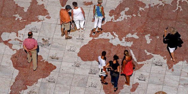 People walk over a world map engraved in marble in Lisbon September 14, 2011. Global markets have been roiled since the end of July by the twin fears of a recession in the United States and Europe's protracted debt woes, which have forced Greece, Ireland and Portugal to take bailouts and piled bond market pressure on Italy and Spain. REUTERS/Jose Manuel Ribeiro (PORTUGAL - Tags: POLITICS BUSINESS)