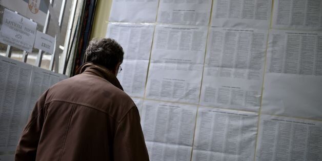 A man checks the list of all the candidates at a polling station in Belgrade on April 24, 2016. Serbians...