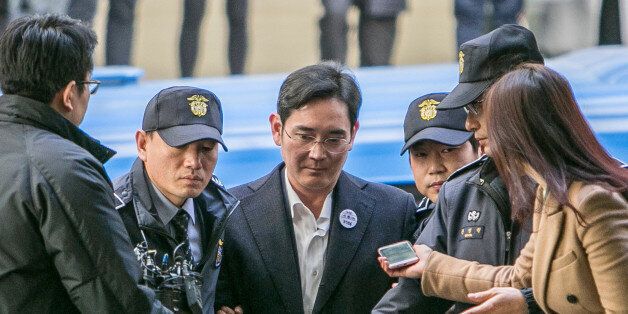 Jay Y. Lee, co-vice chairman of Samsung Electronics Co., center, is escorted by police officers as he arrives at the special prosecutors' office in Seoul, South Korea, on Saturday, Feb. 18, 2017. Lee was formally arrested on allegations of bribery, perjury and embezzlement, an extraordinary step that jeopardizes the executive's ascent to the top role at the world's biggest smartphone maker. Photographer: Jean Chung/Bloomberg via Getty Images