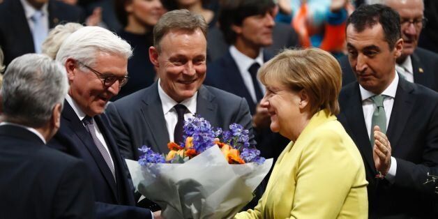 German Chancellor Angela Merkel (R) hands over flowers to new elected German President Frank-Walter Steinmeier (2L) after the presidential election at the Bundesversammlung federal assembly Bundestag (lower house of parliament)on February 12, 2017 in Berlin. Germany's former foreign minister Frank-Walter Steinmeier of the centre-left Social Democrats was elected as the country's ceremonial president in a vote held in the national parliament. / AFP / Odd ANDERSEN (Photo credit should read