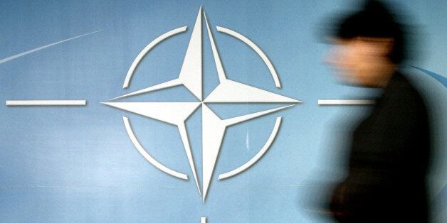 A woman walks past the NATO logo at the entrance of the Alliance headquarters ahead of a NATO foreign ministers meeting in Brussels December 4, 2003. Transatlantic strains over EU defence ambitions were set to overshadow a session of NATO foreign ministers on Thursday, as they did when the alliance's defence ministers met earlier in the week.