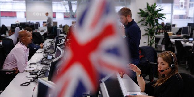 A trader speaks on telephone headset as she looks at financial data on computer screens, while a Union Flag, also known as a Union Jack, flies from office furniture in the foreground on the trading floor at ETX Capital, a broker of contracts-for-difference, in London, U.K. on Friday, Oct. 14, 2016. It's been a tumultuous two weeks for the pound, and all indications are that traders will have to get used to the volatility. Photographer: Luke MacGregor/Bloomberg via Getty Images