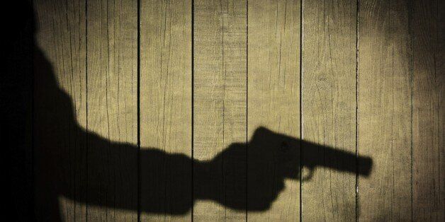 Man in the Shadows with handgun, on natural wooden background, with space for text or image.