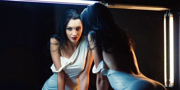 Portrait of a beautiful young woman looking into the mirror