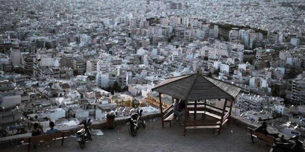 People sit on benches at a hill overlooking the city of Athens on September 15, 2013. With Greece in a six-year recession, having narrowly escaped bankruptcy with the help of EU-IMF loans in 2010, and with a storm of new taxes hitting property owners, real estate is all but dead. Building activity in Greece tumbled by 44 percent in the first quarter of the year compared to a year earlier, state statistics show. In the construction business proper, recent studies point to a loss of over 185,000 jobs since 2010, namely half of those previously employed in the sector. AFP PHOTO / LOUISA GOULIAMAKI (Photo credit should read LOUISA GOULIAMAKI/AFP/Getty Images)