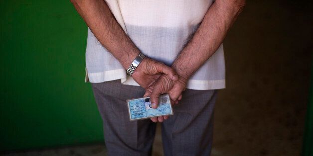 A man holds his ID card as he waits for his turn to cast his vote at a polling station in Athens, Sunday, July 5, 2015. Greeks were voting Sunday in a critical bailout referendum, with opinion polls showing people evenly split on whether to accept creditors' proposals for more austerity in exchange for rescue loans, or defiantly reject the deal. (AP Photo/Emilio Morenatti)