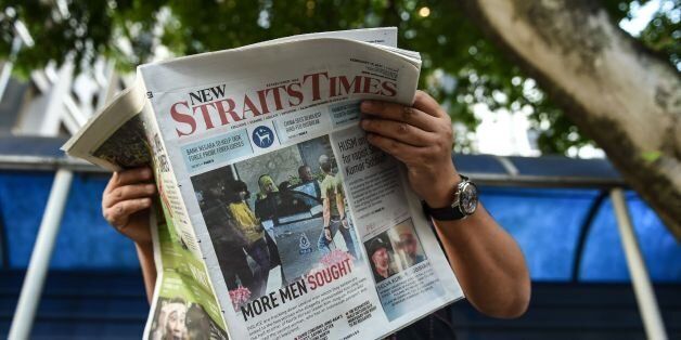 A journalist reads a newspaper with reports about the killed of North Korean man suspected to be Kim Jong-Nam, half-brother of North Korean leader Kim Jong-Un outside the Forensic department at Kuala Lumpur Hospital in Kuala Lumpur on February 17, 2017. Malaysia will return the body of the half-brother of North Korea's leader, the country's deputy prime minister said on February 16, as police probing the airport assassination arrested a second woman. / AFP / MOHD RASFAN (Photo credit should read MOHD RASFAN/AFP/Getty Images)