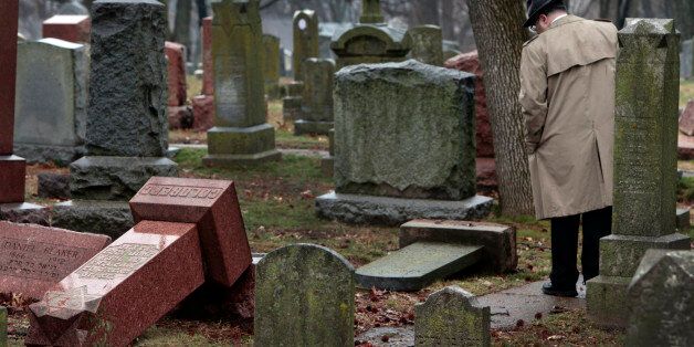People walk through toppled graves at Chesed Shel Emeth Cemetery in University City on Tuesday, Feb. 21, 2017 where almost 200 gravestones were vandalized over the weekend. (Robert Cohen/St. Louis Post-Dispatch/TNS via Getty Images)
