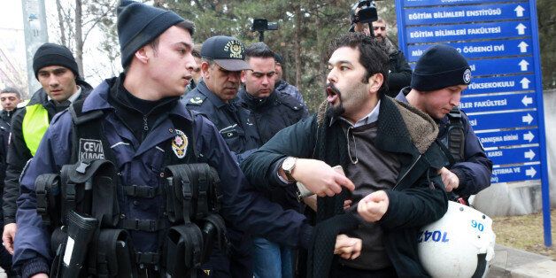 A riot policeman (L) looks at a demonstrator who is detained as Turkish riot police intervene during a protest outside a university campus in Ankara on February 10, 2017, against the dismissal of academics from universities following a post-coup emergency decree. / AFP / ADEM ALTAN (Photo credit should read ADEM ALTAN/AFP/Getty Images)