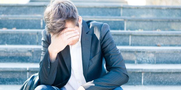 Young business man crying abandoned lost in depression sitting on ground street concrete stairs suffering emotional pain, sadness.